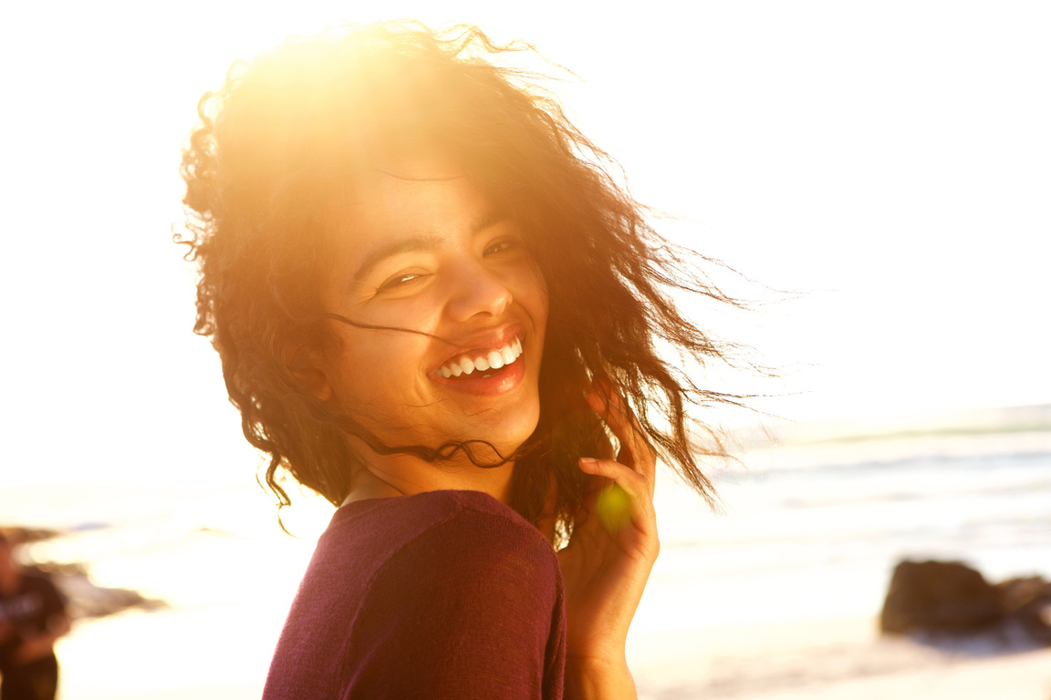Carefree Young Woman with Curly Hair Laughing Outdoors