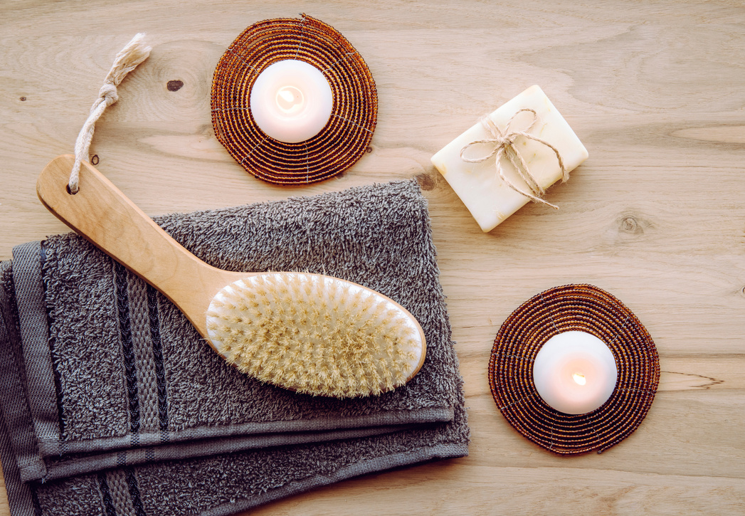 Dry brushing the skin in a pattern with a dry brush, usually before showering help reduce cellulite and remove toxins in human body. Selective focus on firm, natural bristle brush with a long handle.